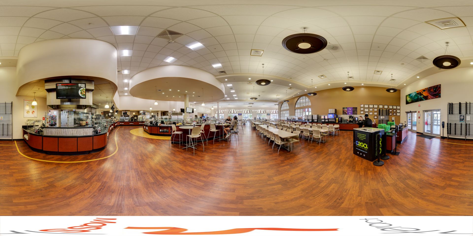 Panoramic view of a spacious college dining hall with multiple seating areas, food service counters, and modern lighting